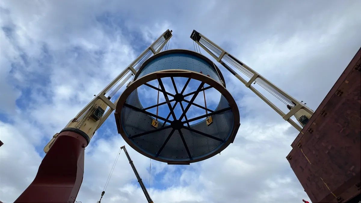 Large circular project cargo suspended between two ship cranes