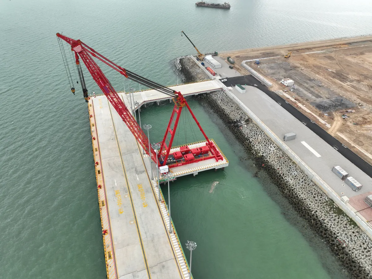 Aerial view of port infrastructure and a red heavy-lift crane